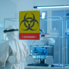 Technician in full PPE conducting biological safety cabinet testing inside a sterile containment laboratory